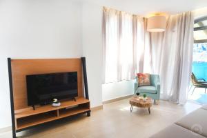 a living room with a flat screen tv and a chair at Blue Horizon Apartment in Kalymnos