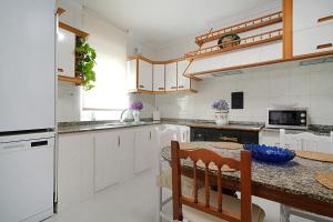 a kitchen with white cabinets and a wooden table at GALIHOST - Enorme casa con gran zona exterior en Cambados in Cambados