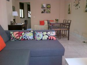 a living room with a blue couch with pillows at Apartamento Venecia Arenal in Seville +7 photos