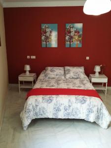 1 dormitorio con 1 cama grande en una pared roja en Apartamento Venecia Arenal, en Sevilla