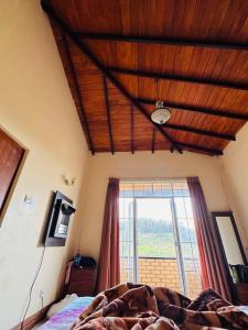 a bedroom with a wooden ceiling and a bed with a window at The Vatican Villa in Nuwara Eliya