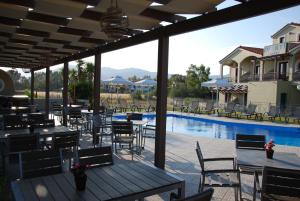 eine Terrasse mit Tischen und Stühlen neben einem Pool in der Unterkunft Imerti Resort Hotel in Skala Kallonis