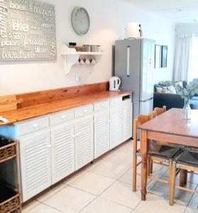 a kitchen with a table and a refrigerator at Mclaren Self Catering in Gansbaai +16 photos