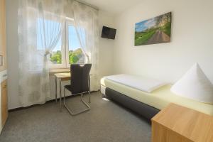 a bedroom with a bed and a desk and a window at Frühstückspension Zur Krone in Bad Endbach
