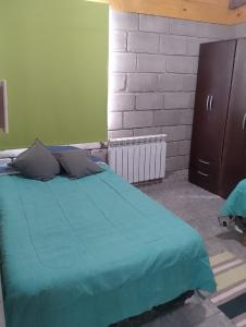 a bedroom with a bed with a green blanket at Los Duraznillos in Los Antiguos