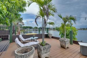 una terraza con palmeras, mesa y sillas en Lakefront Getaway with Dock Near Las Olas Beach, en Fort Lauderdale