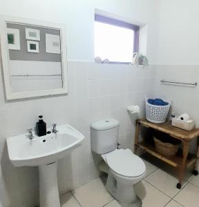 a white bathroom with a toilet and a sink at Mclaren Self Catering in Gansbaai
