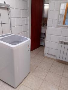 a white washing machine sitting on a tile floor in a kitchen at Los Duraznillos in Los Antiguos