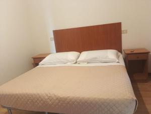 a bedroom with a large bed with a wooden headboard at Hotel Astor Lago in Magione +5 photos