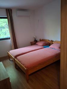 a bedroom with two beds with pink sheets and a window at The Byala Escape, Private Villa with Bar & Hot Tub in Byala