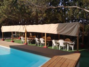 a tent with tables and chairs next to a swimming pool at Le Cyprès in Saint-Mitre-les-Remparts