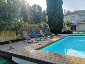 a deck with chairs next to a swimming pool at Le Cyprès in Saint-Mitre-les-Remparts +12 photos