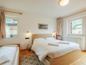 a bedroom with a large bed and two windows at Apartment Erika by Interhome in Canazei