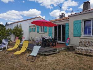 a patio with a table and chairs and a red umbrella at La Villa in La Tranche-sur-Mer