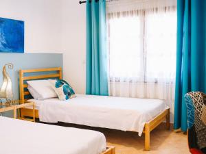 twee bedden in een kamer met blauwe gordijnen bij Apartment Crystal Sea Apartment by Interhome in Santa Maria Navarrese