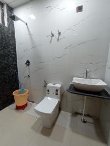 a bathroom with a white toilet and a sink at NBR SADAN Hotel in Govardhan +12 photos