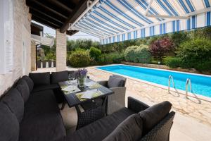 a patio with a table and chairs next to a swimming pool at Casa di Oliva in Brtonigla