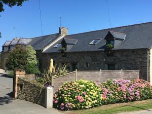 una casa con una valla y flores delante de ella en Gite, en Saint-Denoual