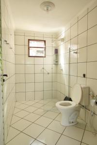 a white bathroom with a toilet and a shower at Itapuã Pousada e Hostel Corais in Salvador
