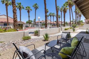a patio with chairs and tables and palm trees at Palm Springs Abode with Pool Access, Near Golfing in Palm Springs