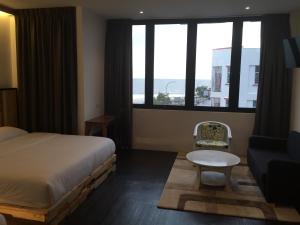 een slaapkamer met een bed, een bank en een raam bij The Oikos Hotel in Pontian Kecil