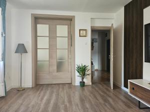 a hallway with a wooden door and a potted plant at Apartman Mano in Topla