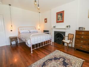 a bedroom with a bed and a chair and a fireplace at The Retreat at Glanrannell Park House in Llanwrda