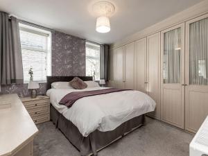 Un dormitorio con una cama, un escritorio y ventanas. en The Crows Nest, en Buxton