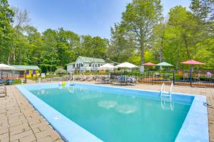 a large blue swimming pool with tables and umbrellas at Screened Porch and Fire Pit Cabin Near Bethel Woods in Mongaup Valley