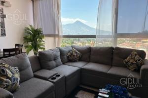 Una sala de estar con un sofá y una ventana grande. en Volcano Views Apartment, en San Salvador