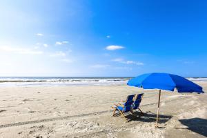 a blue chair and an umbrella on the beach at Lazy Lagoon in Kiawah Island