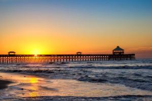 a pier on the beach with the sun setting at Lazy Lagoon in Kiawah Island