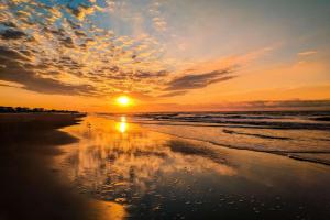 a sunset on a beach with the sun setting at Lazy Lagoon in Kiawah Island