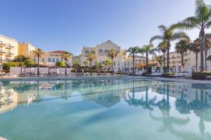 a large swimming pool with palm trees and buildings at Vilamoura Marina Lake in Vilamoura