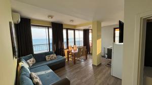 a living room with a couch and a view of the ocean at Апартаменти и студия в комплекс Акротирия in Nesebar