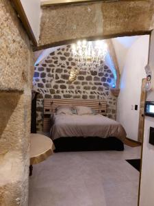 Un dormitorio con una cama en una pared de piedra. en La parenthèse Ponote - Hammam - WIFI - city center, en Le Puy en Velay
