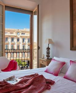 um quarto com uma cama e uma grande janela em Lodgingmalaga Plaza Constitucion em Málaga