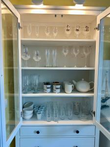 Un armario lleno de vasos, cuencos y otros artículos. en Les Jardins d'Opale 1, en Le Touquet-Paris-Plage