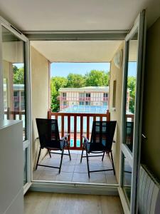 a balcony with two chairs and a view of a building at Les Jardins d'Opale 1 in Le Touquet-Paris-Plage