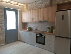 a kitchen with wooden cabinets and a refrigerator and a door at isogion in Pitsidia