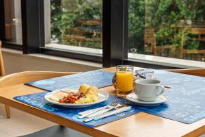 a table with a plate of breakfast food and a cup of orange juice at Rio Hotel by Bourbon Maringá in Maringá
