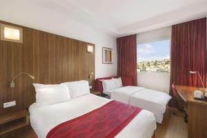 una camera d'albergo con due letti e una scrivania di Ramada Encore By Wyndham Tangier a Tangeri Altre 37 foto