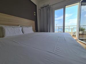 a bedroom with a large white bed with a large window at Manas Rooms in Dhërmi
