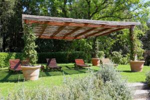 a group of chairs under a wooden pergola in a garden at Hotel La Collegiata - Adults Only in San Gimignano +77 photos