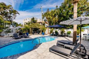 a swimming pool with patio furniture and umbrellas at The Inn on Siesta Key in Siesta Key