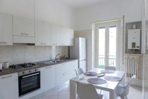 a kitchen with white cabinets and a table with chairs at Luma Casa Vacanze in Gaeta