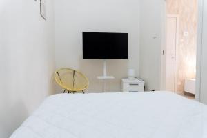 a white bedroom with a white bed and a yellow chair at Luma Casa Vacanze in Gaeta