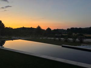 a sunset over a swimming pool in a yard at Noyau & Pepin in Rognes