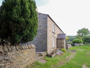 an old stone house with a tree next to it at Rosemary Cottage in Leyburn