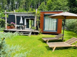 a couple of chairs and an umbrella in a yard at HJEM - Tiny Homes direkt am Wald zwischen Allgäu & Bodensee in Bergatreute
